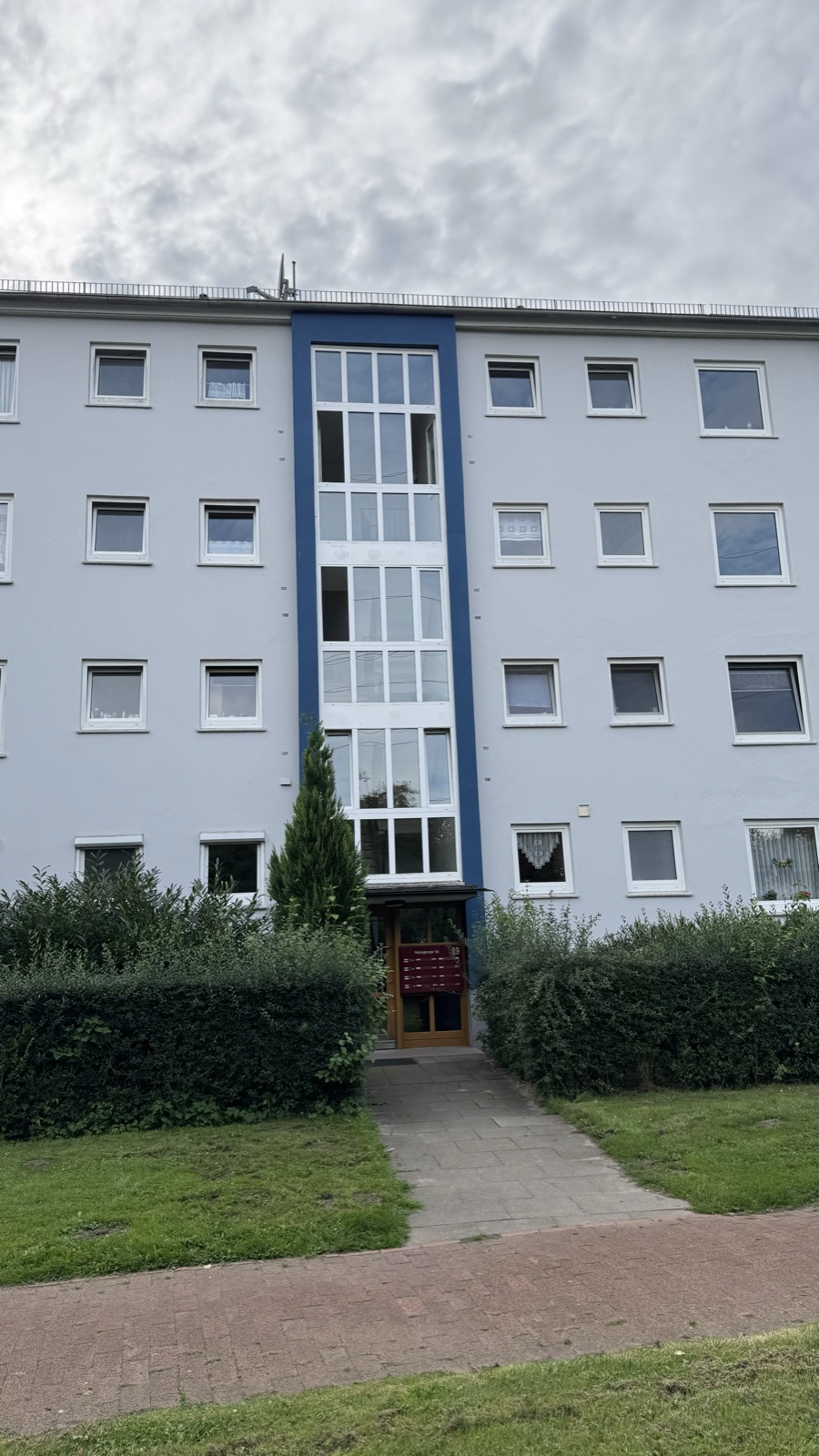 Helle Wohnhausfassade mit blau abgesetztem Treppenhaus